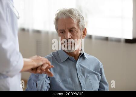 Nahaufnahme junge Krankenschwester tröstend depressiv reifen Patienten, Hände halten Stockfoto