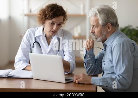 Selbstbewusster Arzt, der den reifen Patienten bei einem medizinischen Termin konsultiert Stockfoto