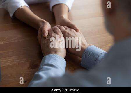 Nahaufnahme junge Frau Krankenschwester hält die Hände von reifen Patienten Stockfoto