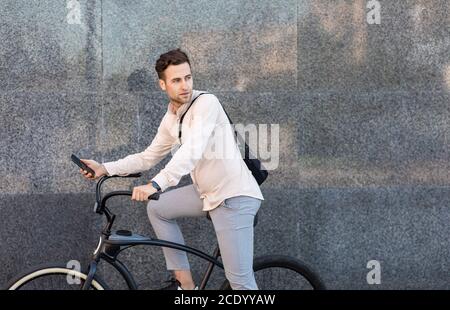 Ökologisches Transportkonzept. Seriöser Mann mit Tasche fährt auf dem Fahrrad und schaut weg Stockfoto