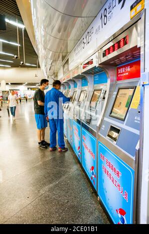 Zwei Männer kaufen U-Bahn-Tickets von einer Reihe von Maschinen in Shanghai People’s Square U-Bahn-Station. Stockfoto