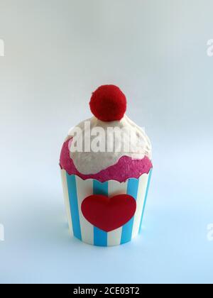 Cupcake rosa Schlagsahne mit rotem Herz und Ball rot auf weißem Hintergrund dekoriert. Muffin blau e weiß Streifen Dekoration Linie. Süße Lebensmittel Stockfoto