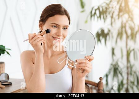 Glücklich hübsches Mädchen Anwendung Rouge auf ihr Gesicht Stockfoto