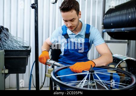 Arbeiter mit Werkzeugmaschine installiert Fahrradspeichen Stockfoto