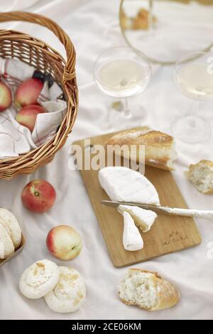 Sommer - Picknick. Käsebre, Baguette, Pfirsiche, Champagner und Korb Stockfoto