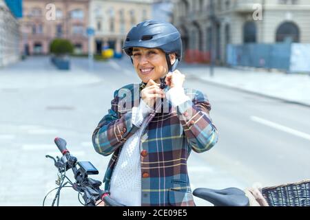 Junge Frau Putting Fahrrad Schutzhelm auf der Straße Stockfoto