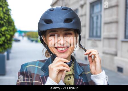 Portrait der jungen Frau Putting Fahrrad Schutzhelm Stockfoto