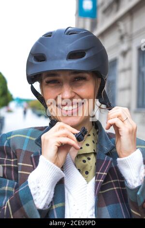 Portrait der jungen Frau Putting Fahrrad Schutzhelm Stockfoto