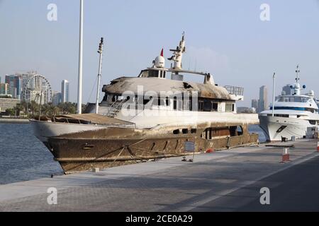 Ein kleiner verbrannter Stahl privater No Name Handelsboote gegen Der Hintergrund der städtischen Wolkenkratzer Dubai Stockfoto