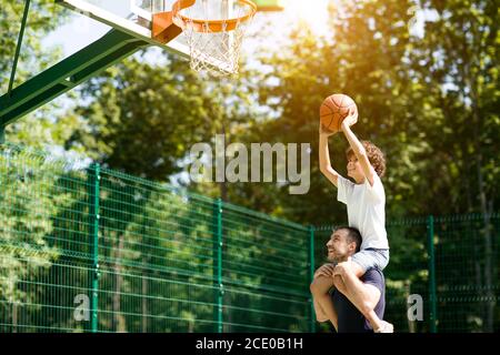 Glücklicher Vater hilft seinem Baby, einen Korb zu bekommen Stockfoto