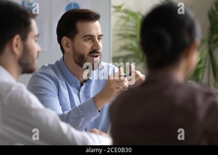 Glücklicher junger Geschäftsmann diskutiert Projekt mit Kollegen. Stockfoto