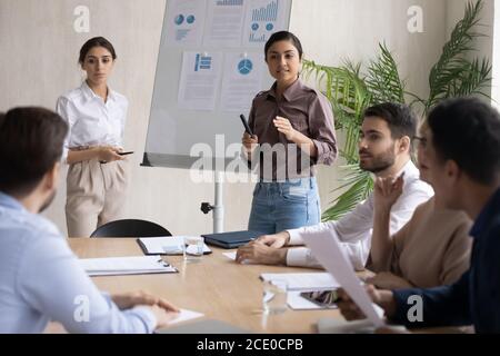 Fokussierte junge multirassische weibliche Sprecher präsentieren Marketing-Strategie. Stockfoto