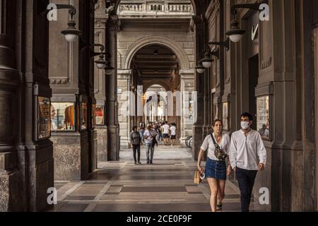 Menschen, die unter Arkaden in Bologna, Italien, spazieren Stockfoto