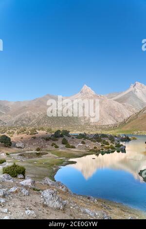 Der Pamir-Bergblick und ruhiger Campingplatz am Kulikalon-See im Fann-Gebirge in Tadschikistan. Bunte Reflexion in pur aufmuntern Stockfoto