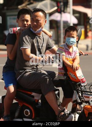 Peking, China. August 2020. Chinesen mit Gesichtsmasken fahren am Sonntag, den 30. August 2020, mit einem E-Bike eine Straße in Peking entlang. Obwohl Chinas Hauptstadt das obligatorische Tragen von Gesichtsmasken im Freien aufgehoben hat, schützen sich viele Chinesen aufgrund der möglichen Rückkehr des Coronavirus weiterhin. Laut US-Geheimdiensten hielten Beamte in Wuhan Peking wochenlang im Dunkeln über die mögliche Verwüstung des Coronavirus. Foto von Stephen Shaver/UPI Kredit: UPI/Alamy Live Nachrichten Stockfoto