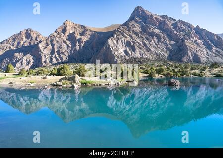 Der Pamir-Bergblick und ruhiger Campingplatz am Kulikalon-See im Fann-Gebirge in Tadschikistan. Bunte Reflexion in pur aufmuntern Stockfoto