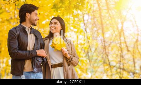 Romantisches lächelndes Paar, das durch den Herbstpark spazierengeht Stockfoto