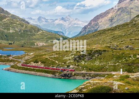 BERNINA Express-Zug am Weissen See in Ospizio Bernina, Oberengadin, Graubünden, Graubünden, Schweiz. Stockfoto