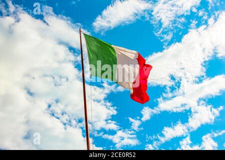 Italien Flagge winkt auf blau wolkigen Himmel, grün weiß und rot Farben. Symbol der italienischen Armee. Stockfoto