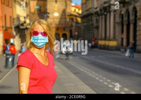 Frau posiert mit einer chirurgischen Maske und Sonnenbrille in Bologna Stadt. COVID-19 Quarantäne der Stadt Bologna in Italien, Tag nach. Stockfoto