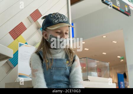 Baby Mädchen mit traurigen Augen in einer schützenden medizinischen Maske am Flughafen während einer Coronavirus Quarantäne. Stockfoto
