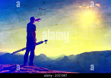 Filmkörnung. Professioneller Fotograf mit Stativ auf Klippe und Denken. Verträumte Fogy Landschaft, blau nebligen Sonnenaufgang in einem schönen Stockfoto