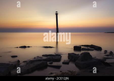 Leuchtturm Kiipsaare in Saaremaa, Estland. Ikonisches lokales Wahrzeichen - schräg verlassene Leuchtturm. Sonnenuntergang mit einem rot gefärbten Himmel. Stockfoto