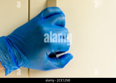 Männliche Hand in Gummihandschuhen, die den Türgriff während des Covid halten 19 Sperre Stockfoto