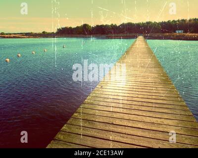 Filmeffekt. Leerer hölzerner Maulwurf am blauen See, Anlegestelle für gemietete Boote in der Marina. Bereit für Reiseschiffe. Stockfoto