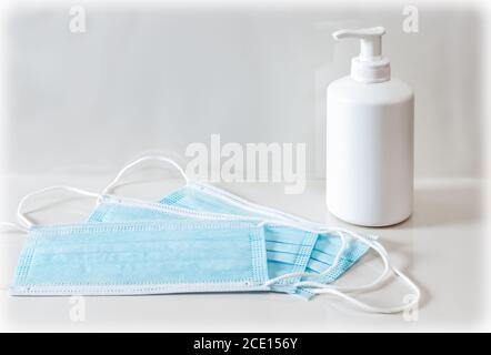 Blaue medizinische Maske und Händedesinfektionsgel oder Seifenspender. Coronavirus-Präventionskonzept Stockfoto