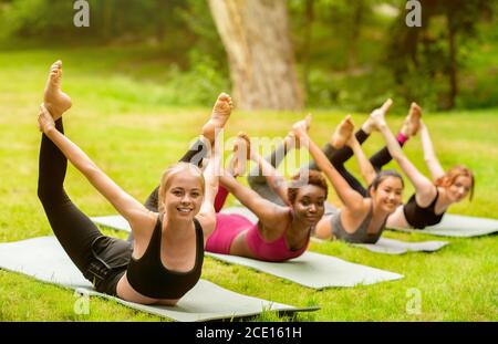 Diverse Millennial Mädchen tun Bogen Yoga Asana auf Outdoor-Gruppe Übung Stockfoto