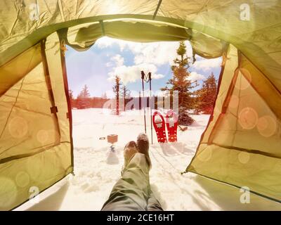 Zelt in Winterlandschaft. Trekkingzelt, Stöcke, rote Schneeschuhe auf Schnee Stockfoto