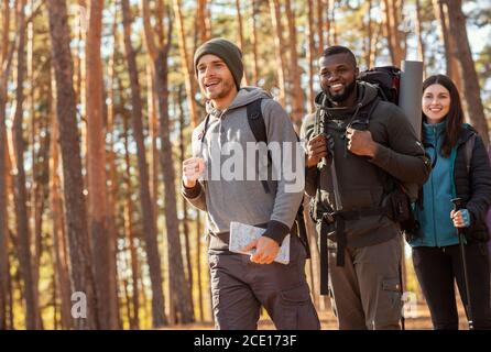 Drei fröhliche multirassische Freunde wandern durch den Wald Stockfoto