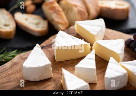 In Scheiben geschnittener Brie-Käse oder Camembert auf Holzbrett. Leckerer französischer Weichkäse Stockfoto