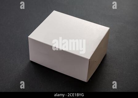 Paket Box Rechteck, leer inserieren Vorlage für Produkte Verpackung. Weiße Farbe leerer geschlossener Kartonbehälter vor schwarzem Hintergrund Stockfoto