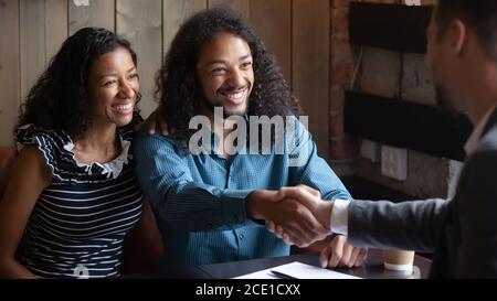 Lächelnder afroamerikanischer Mann schüttelt makler Hand, Familie macht Deal Stockfoto