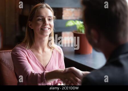 Lächelnde junge Frau schüttelt Mann Hand bei der Sitzung im Café Stockfoto