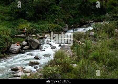 Zwei Fischer genießen Angeln durch die Überquerung des Flusses durch ein Bambusbrücke in einem Wald in Sikkim in Indien Stockfoto