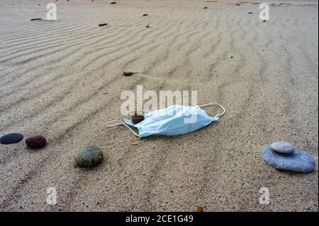 Schützende Stoffmaske am Meeresstrand, medizinische Maske auf dem Sand Stockfoto