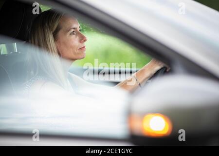 Hübsche Frau im mittleren Alter am Steuer von ihr Auto pendeln zur Arbeit Stockfoto