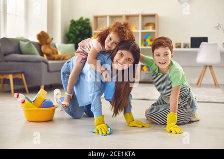 Glückliche Mutter mit ihren Kindern Reinigung Boden in der Wohnung. Eltern mit Kindern Spaß haben, während Hausarbeit zu tun Stockfoto