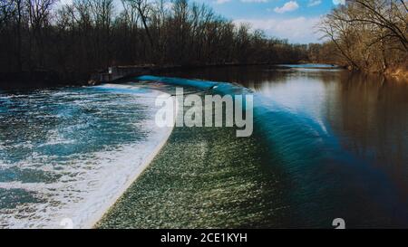 Schnell fließendes Wasser stürzt über einen von Menschen gemachten Staudamm in ein Toter Winterwald Stockfoto