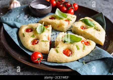 Italienisches Focaccia-Brot in Scheiben mit Tomaten und Basilikum Stockfoto