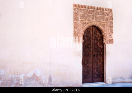 Kalligraphie und Motive umgeben die geschnitzte Tür im Alhambra Palace, Granada, Spanien. Stockfoto