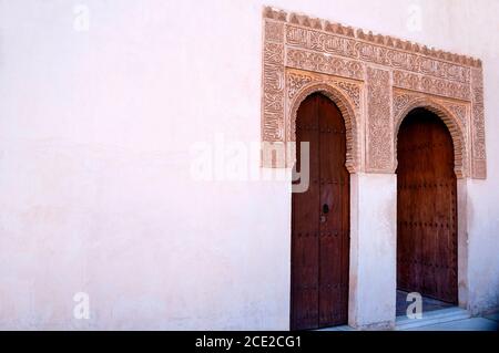 Kalligraphische Botschaften und Motive umgeben geschnitzte Türen an der Alhambra in Granada, Spanien. Stockfoto