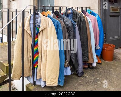 Second Hand Kleidung, die an einem Kleiderständer vor einem Geschäft in Stockbridge, Edinburgh, Schottland, Großbritannien, hängt. Stockfoto