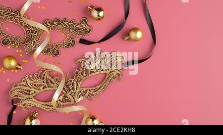 Goldene Maskerade Masken, Party Streamer, Weihnachtskugeln Dekorationen auf pastellrosa Hintergrund. Flach liegend, Draufsicht. Bannermockup im Luxusstil für Chr. Stockfoto