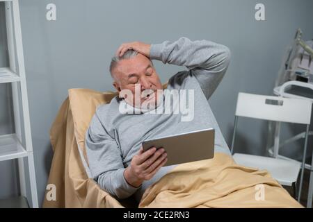 Medizin, Alter, Gesundheitswesen und Menschen Konzept - ein älterer Patient schaut ein Sportspiel auf seinem digitalen Tablet in einer Krankenhausstation, das Spiel ist nicht g Stockfoto