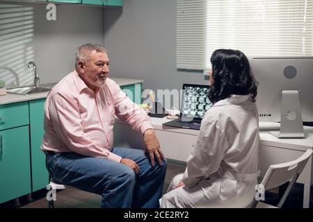 Eine professionelle Ärztin, die ihrem Patienten die Ergebnisse der Diagnose zeigt. Stockfoto
