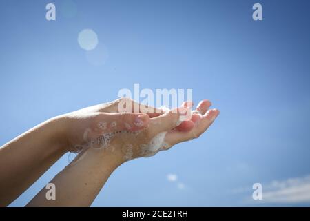 Nahaufnahme Frau Hände mit Seifenblasen auf blauem Himmel Hintergrund Stockfoto